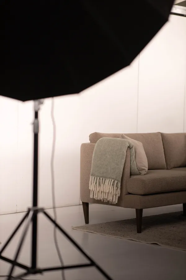 Sesja zdjęciowa mebli tapicerowanych w studiu - sofa oświetlona profesjonalną lampą studyjną